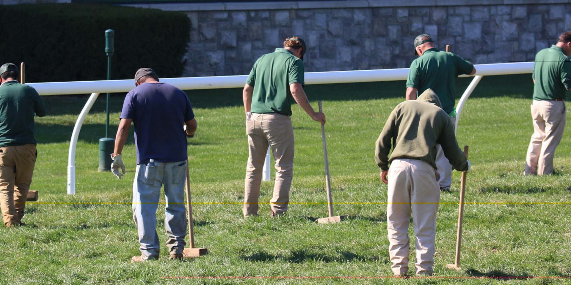 An action shot of Racetrackelite team members tamping down turf divots.